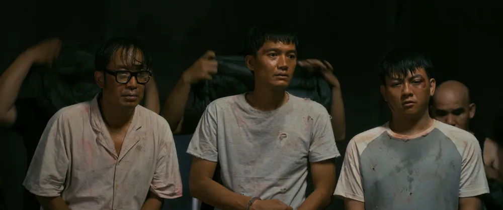 Trong căn phòng chật hẹp, ánh sáng tù mù, một người bị trói và đánh đập dã man, trong khi xung quanh là hàng chục người khác vẫn dửng dưng cắm mặt vào máy tính.